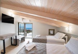 a bedroom with two beds and a desk and a television at Villelia View Villas 2 in Apolpaina