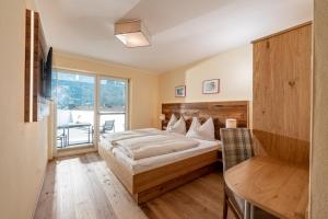 a bedroom with a bed and a table and a window at Hotel Die Metzgerstubn in Sankt Michael im Lungau