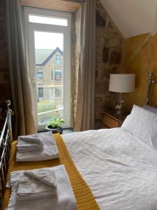 een slaapkamer met een bed met handdoeken en een raam bij Shoreline in St Ives