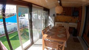 a dining room with a table and a kitchen with a view at Les margouillats - maisonnette à 2 pas de la plage in Vias