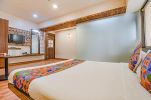 a bedroom with a large bed and a desk at FabExpress Glory in Chinchiwad