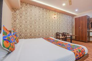 a bedroom with a bed and a table with a chair at FabExpress Glory in Chinchwad