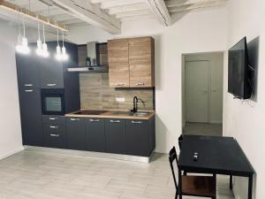 a kitchen with black cabinets and a table and a tv at new apartment 2 minute from the port in Livorno