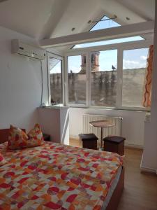 a bedroom with a bed and a table and windows at Casa Drumețului in Făgăraş