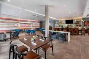 a restaurant with tables and chairs and a bar at Cambria Hotel Nashville Airport in Nashville