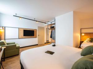 Zimmer mit einem Bett, einem Sofa und einem TV in der Unterkunft ibis Lyon Sud Oullins in Oullins