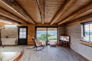 Habitación con silla, TV y pared de ladrillo. en La Cabană en Vişeu de Jos