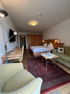 une chambre d'hôtel avec un lit et un canapé dans l'établissement Hotel Goldener Stern, à Abtenau