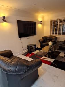 a living room with leather furniture and a flat screen tv at Linx View 4 Bedroom House in Kent