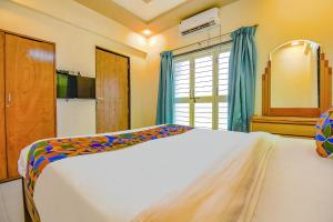 1 dormitorio con cama blanca y ventana en FabHotel Galaxy Inn, en Pune