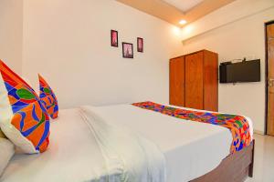 1 dormitorio con 1 cama y TV en la pared en FabHotel Galaxy Inn, en Pune