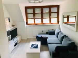 salon z niebieską kanapą i telewizorem w obiekcie KOSI Thermen-Vulkanland Appartement w mieście Fürstenfeld