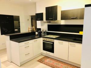 a kitchen with white cabinets and black counter tops at KOSI Thermen-Vulkanland Appartement in Fürstenfeld
