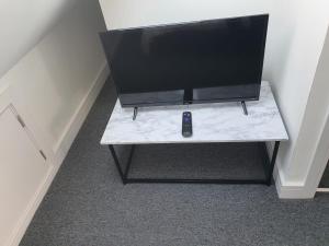 a television on a table with a remote control on it at New Self Contained Flat,in Hayes, Free Parking in Northolt