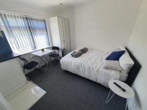 a bedroom with a bed and a table and a window at New Self Contained Flat,in Hayes, Free Parking in Northolt