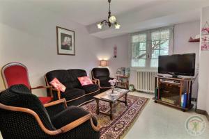 sala de estar con muebles negros y TV de pantalla plana en Gîte Brocéliande, en Baulon