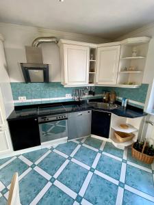 uma cozinha com armários brancos e pisos em azulejo azul em Heidrun's Home em Altendiez