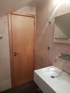 a bathroom with a sink and a wooden door at Bemar Loft in Costa da Caparica +32 photos