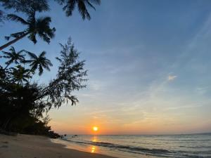 una puesta de sol en una playa con palmeras en Secret Beach Bungalows en Haad Son