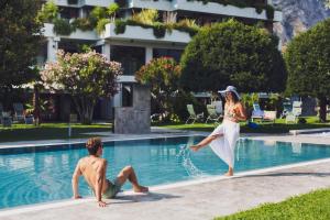 une femme saute dans une piscine avec un homme dans l'établissement Hotel La Fiorita, à Limone sul Garda