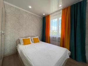a bedroom with a bed with colorful curtains at Квартира целиком с двуспальной кроватью и белым постельным in Petropavlovsk
