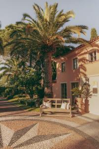 a bench in front of a building with palm trees at La Bastide de Saint Tropez in Saint-Tropez