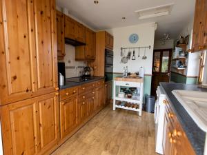 a large kitchen with wooden cabinets and a sink at Pass the Keys Cosy cottage with views over the Shropshire hills in Ludlow