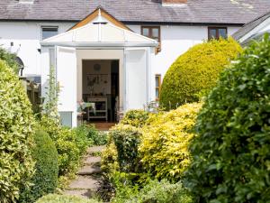 a white house with a pathway leading to the front door at Pass the Keys Cosy cottage with views over the Shropshire hills in Ludlow