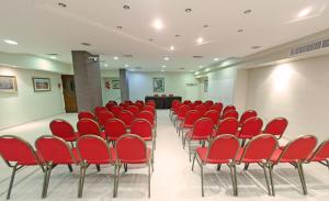 une salle de conférence avec des chaises rouges et un podium dans l'établissement Hotel Centro, à Santiago del Estero