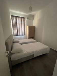 Habitación pequeña con 2 camas y ventana en Westwood 2Bd Apartments en Durrës