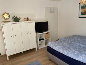 1 dormitorio con 1 cama y TV en un armario en Schöne Wohnung mit Pool und Sauna zum Wohlfühlen, en Oberhausen
