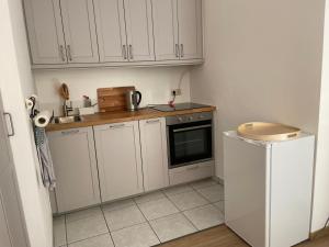 eine kleine Küche mit weißen Schränken und einem Kühlschrank in der Unterkunft Schöne Wohnung mit Pool und Sauna zum Wohlfühlen in Oberhausen