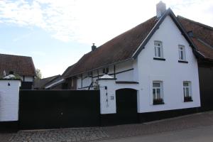 a white house with a black gate in a street at Vakwerkvakantiehuis Eckelmus in Eckelrade