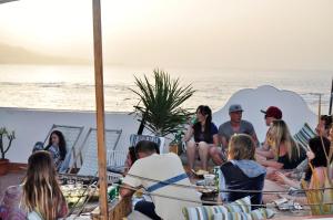 un groupe de personnes assises autour de tables sur la plage dans l'établissement Surf House Gran Canaria, à Las Palmas de Gran Canaria
