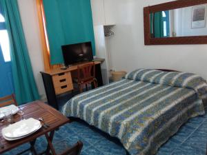 um quarto de hotel com uma cama, uma mesa e uma televisão em Le Tuléar - Résidence Gandhi em Saint-Pierre