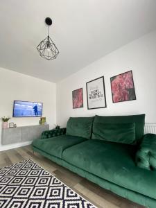 a green couch in a living room with a tv at Velvet Studio in Târgu-Mureş