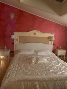 um quarto com uma cama branca e uma parede vermelha em Hotel Due Colonne em San Bonifacio