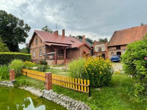 a house with a yellow fence next to a pond at Agroturystyka Szerokopaś in Nidzica