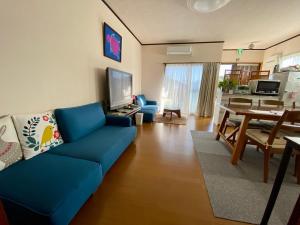 a living room with a blue couch and a dining room at ホライゾン in Oshima