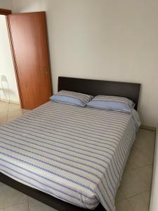 ein Bett mit blau und weiß gestreifter Bettwäsche in einem Schlafzimmer in der Unterkunft Corso Umberto Apartment in Soverato Marina