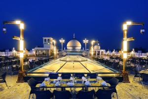 GujrānwālaMUGHAL MAHAL HOTEL的一间餐馆,有人坐在大楼前的桌子上