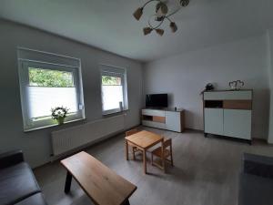 a living room with a couch and a table and two windows at Das Vogelhaus in Hemfurth-Edersee