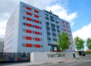 un edificio blanco con ventanas rojas en una calle en Vértice Roomspace, en Madrid