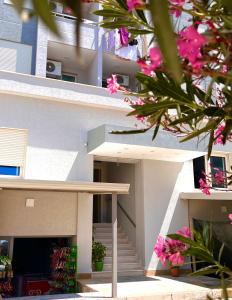 - un bâtiment avec des escaliers et des fleurs roses devant dans l'établissement Flors Apartments, à Durrës