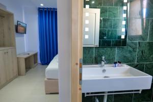 a bathroom with a white sink and a blue shower curtain at Sea View Hotel in Sarandë