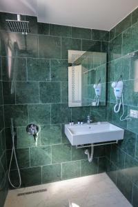 a green tiled bathroom with a sink and a mirror at Sea View Hotel in Sarandë
