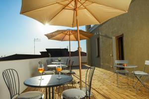 eine Terrasse mit Tischen, Stühlen und Sonnenschirmen in der Unterkunft Casa Mediterranea in Nurachi