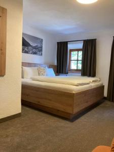 オエッツにあるBrunnfeld Ferienwohnungenのベッドルーム1室(窓の前に大きな木製ベッド1台付)