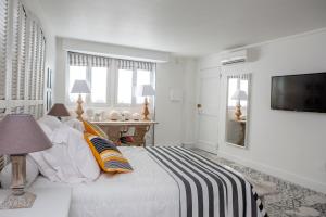 a white bedroom with a bed and a television at L’annexe in Orange