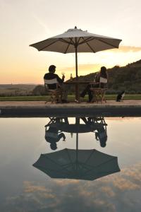 a man and woman sitting at a table with an umbrella at Tenuta Santo Pietro in Pienza